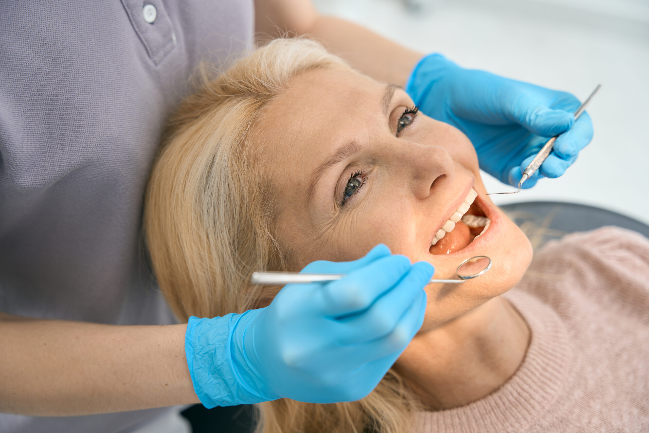Female patient visiting dantist for examining mouth with the mirror.
