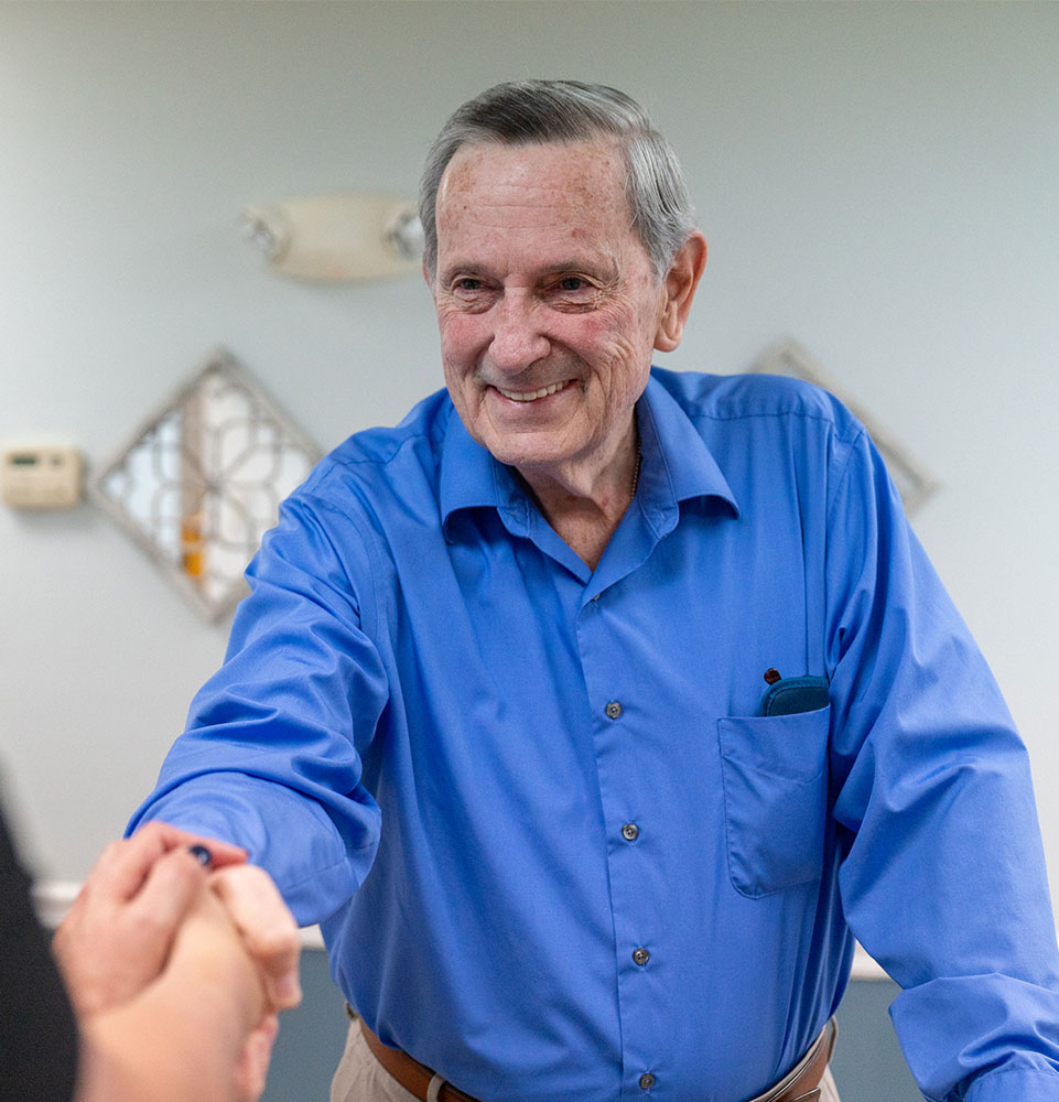 patient smiling brightly while shaking hands at the front desk of the dental center