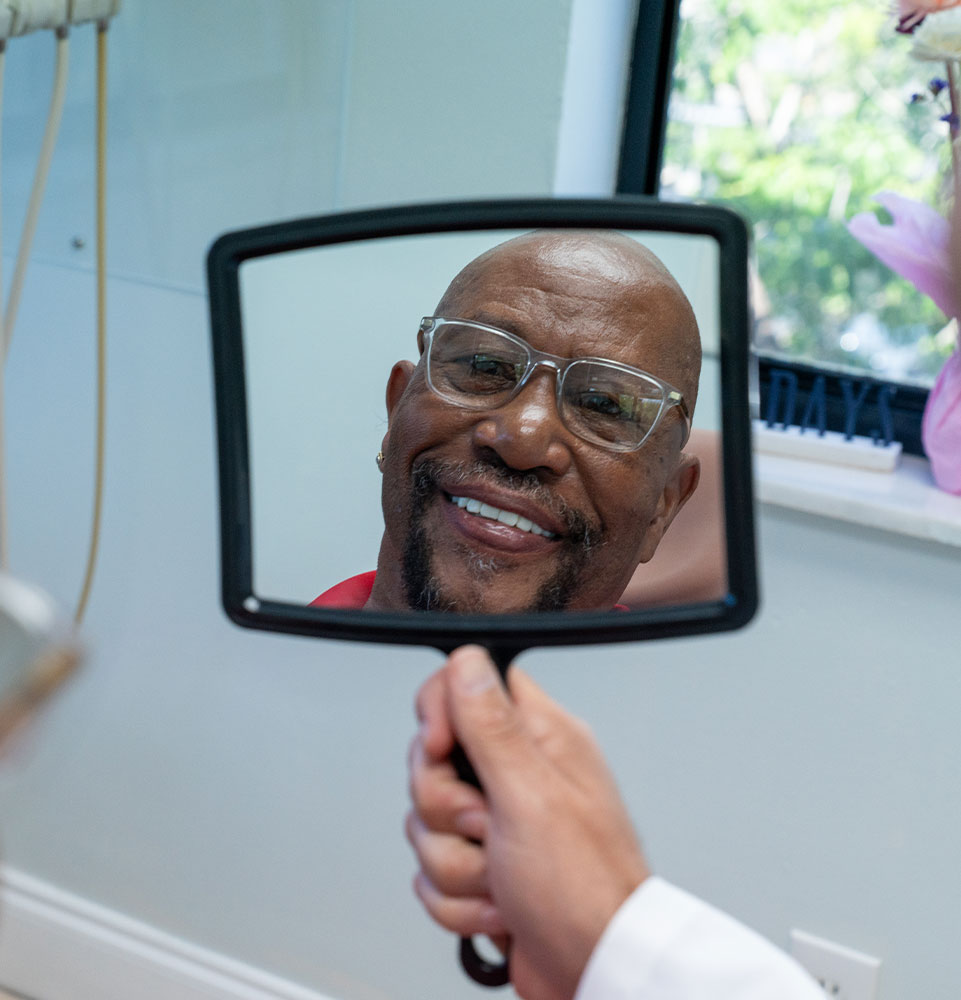 patient smiling brightly in the mirror after dental treatment