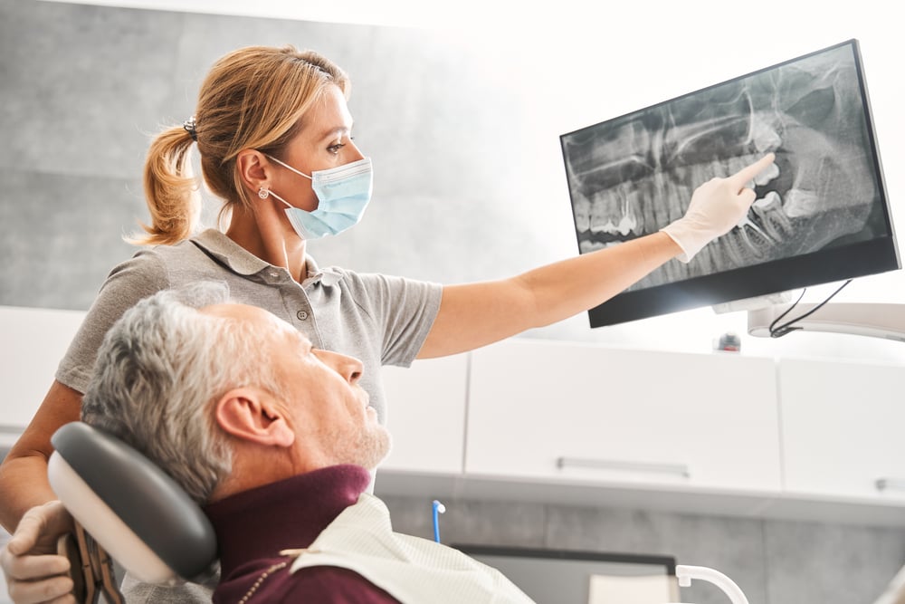 women dentist showing and elderly patient an xray of his teeth