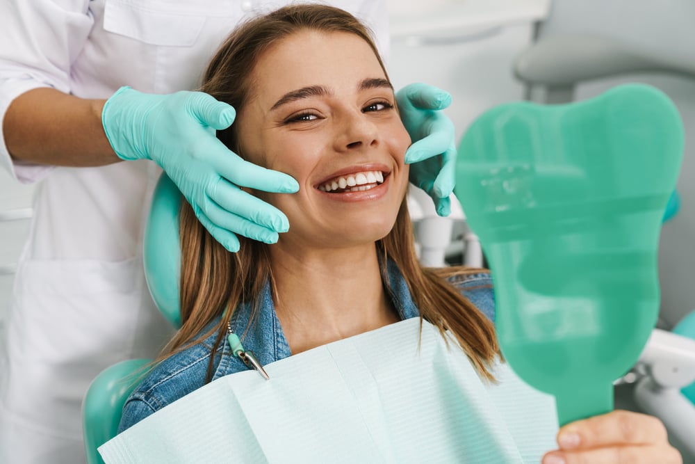 A dentist and patient discussing teeth whitening results in a modern dental office.